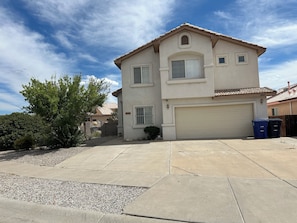 A two-story house with a garage, a driveway, and a small tree in the front yard. - Fantastic 5-bedroom family house with AC in vibrant Albuquerque (Albuquerque)
