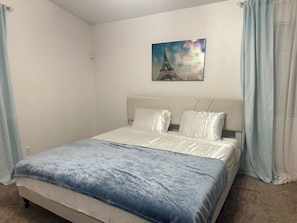 A bedroom with a bed, a headboard, a painting of the Eiffel Tower, and light blue curtains. - Fantastic 5-bedroom family house with AC in vibrant Albuquerque (Albuquerque)