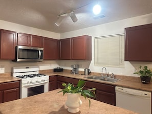 A kitchen with brown cabinets, a microwave, stove, sink, and a dishwasher. - Fantastic 5-bedroom family house with AC in vibrant Albuquerque (Albuquerque)