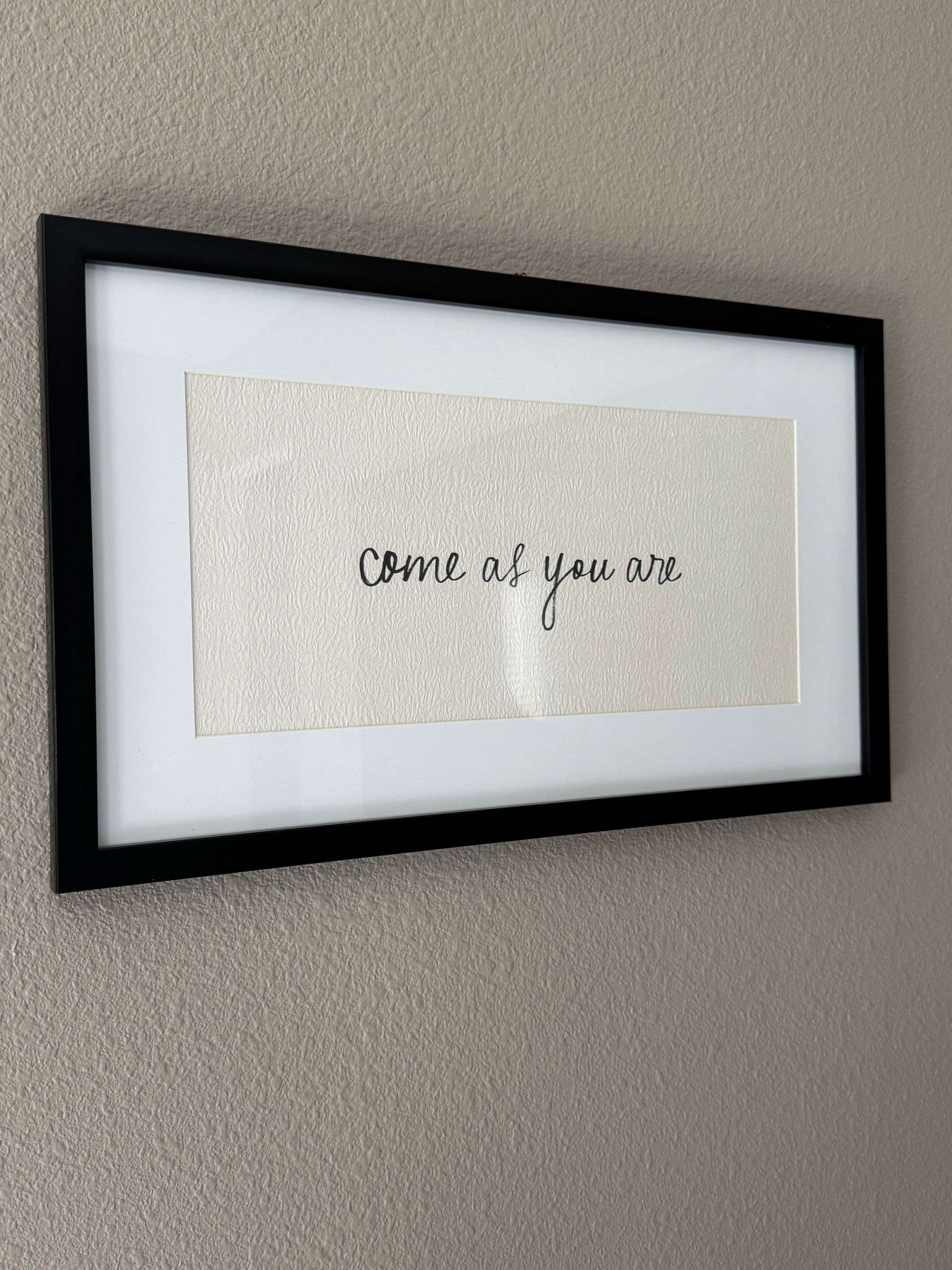 A framed inspirational quote on a textured wall.