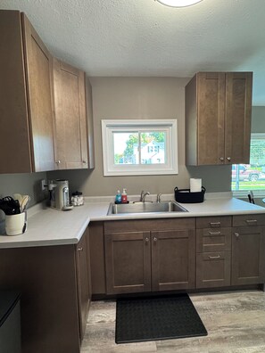 A kitchen with wooden cabinets, a window, a sink, and a coffee maker.