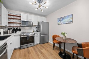 A modern kitchen with white cabinets, stainless steel appliances, and a wooden floor. - AT&T Stadium Area Arlington TX 1 Bed 1 Bath (Arlington)