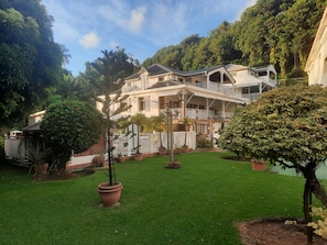 A two-story building with a balcony, surrounded by a well-maintained lawn and potted plants. - THE CREOLE BUTTERFLY (Trois-Rivières)