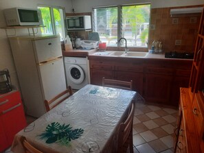 A compact kitchen with a washing machine, a microwave, and a sink. - THE CREOLE BUTTERFLY (Trois-Rivières)