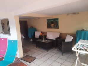 A room with a sofa set, a small table with a vase, and a painting on the wall. - THE CREOLE BUTTERFLY (Trois-Rivières)