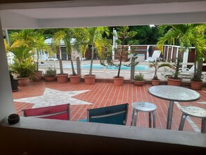 A terrace with potted plants, a pool, and outdoor seating. - THE CREOLE BUTTERFLY (Trois-Rivières)