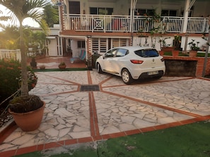 Een witte auto geparkeerd op een geplaveid gebied met een groen gazon en planten in potten.