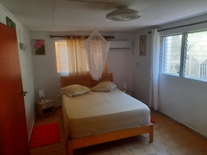 Een slaapkamer met een bed, nachtkastjes, een raam en een deur.