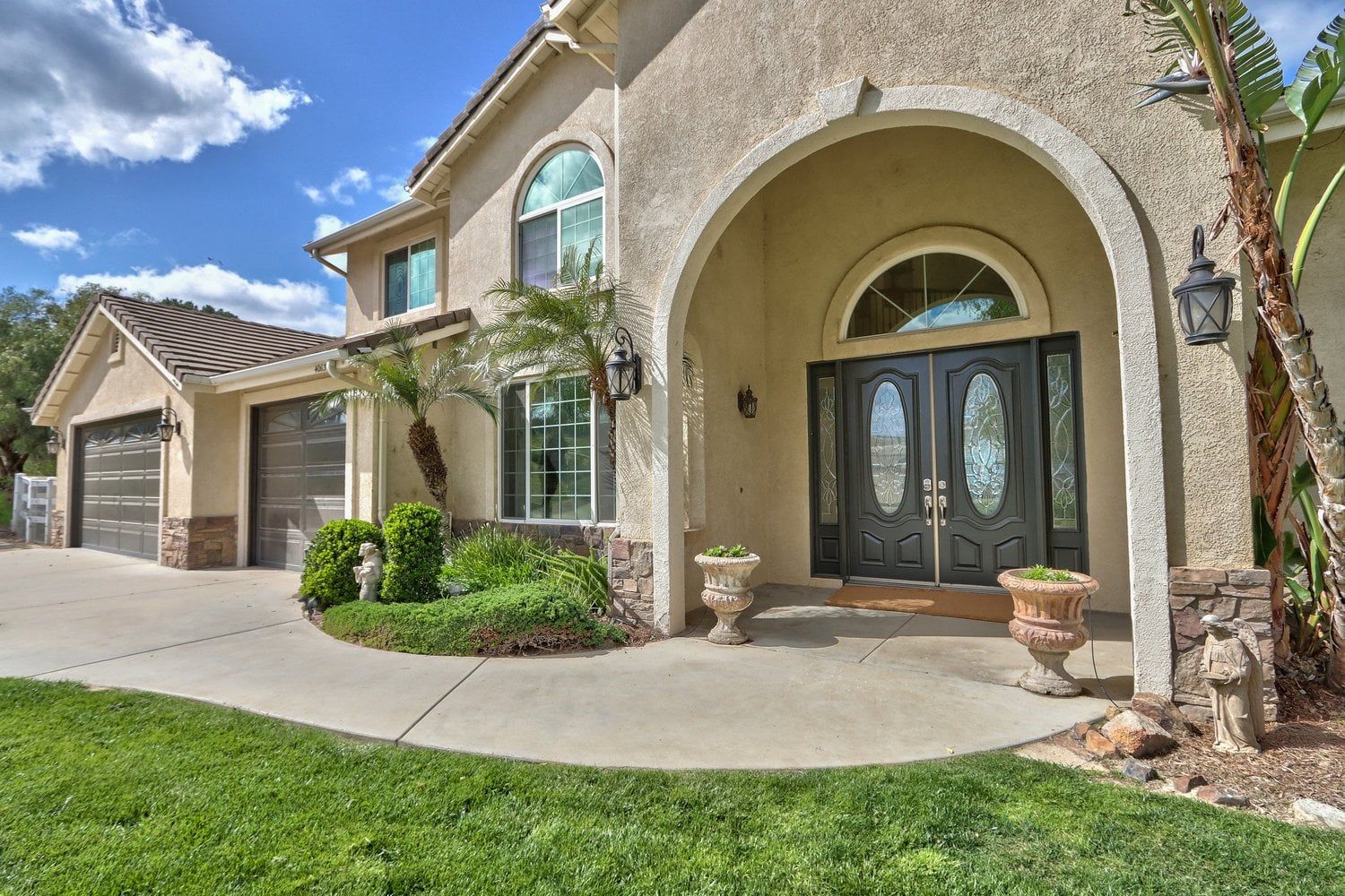 A two-story house with a garage, a front entrance with a decorative door, and a well-maintained lawn.