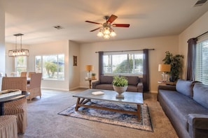 A spacious living room with a ceiling fan, a coffee table, a sofa, and a dining area with chairs. - Casa de Saudade by Fieldtrip | Wine Country Views, Pool, Waterslide & Hot Tub | Sleeps 10 (Temecula)
