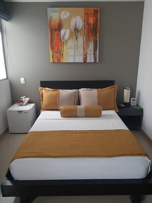 A hotel room with a bed, a nightstand, a lamp, and a painting on the wall. - HOTEL MEDELLIN GOLD (Medellín)