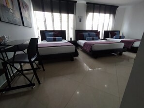 A hotel room with two beds, a desk, and chairs. - HOTEL MEDELLIN GOLD (Medellín)