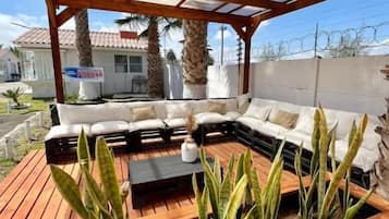 An outdoor seating area with a wooden deck, a cushioned sofa, and potted plants.