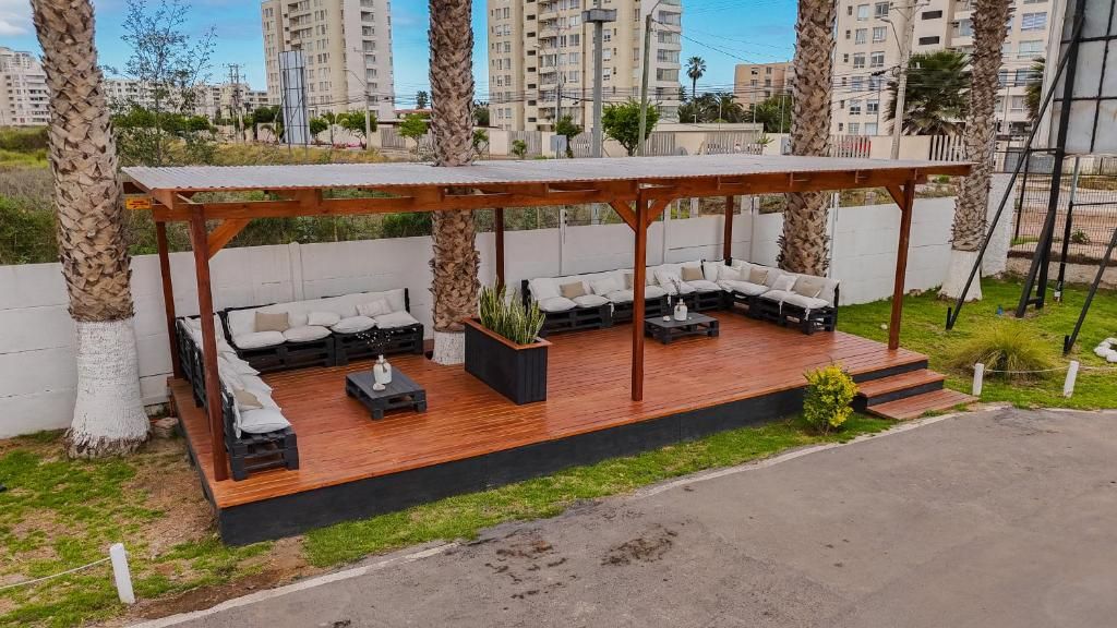 Un patio exterior con terraza de madera, zona de estar y un pérgola.