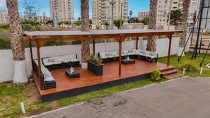 An outdoor patio with a wooden deck, seating area, and a pergola.