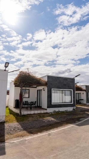 A modern building with a flat roof, large windows, and a small patio area. - Cabañas Pinamar  (Elqui)