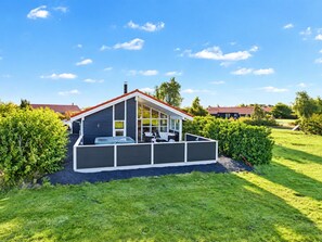 Une maison moderne dotée d’un patio couvert, d’un garage et d’une pelouse bien entretenue.