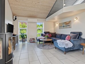 A modern living room with a fireplace, a sofa, a coffee table, and a TV. - "Nelia" - 1km from the sea by Interhome (Væggerløse)