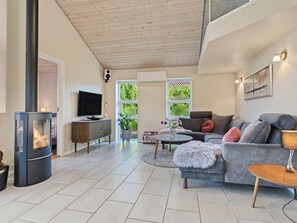 Ein modernes Wohnzimmer mit Kamin, Fernseher und Sofa.