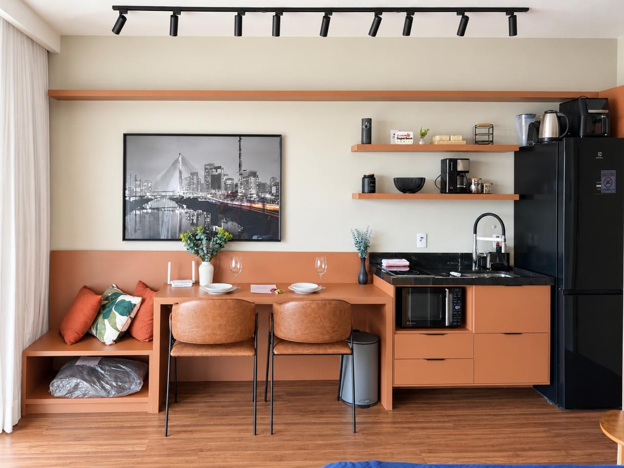 A modern kitchen with a dining area, a black refrigerator, a microwave, and a coffee maker.