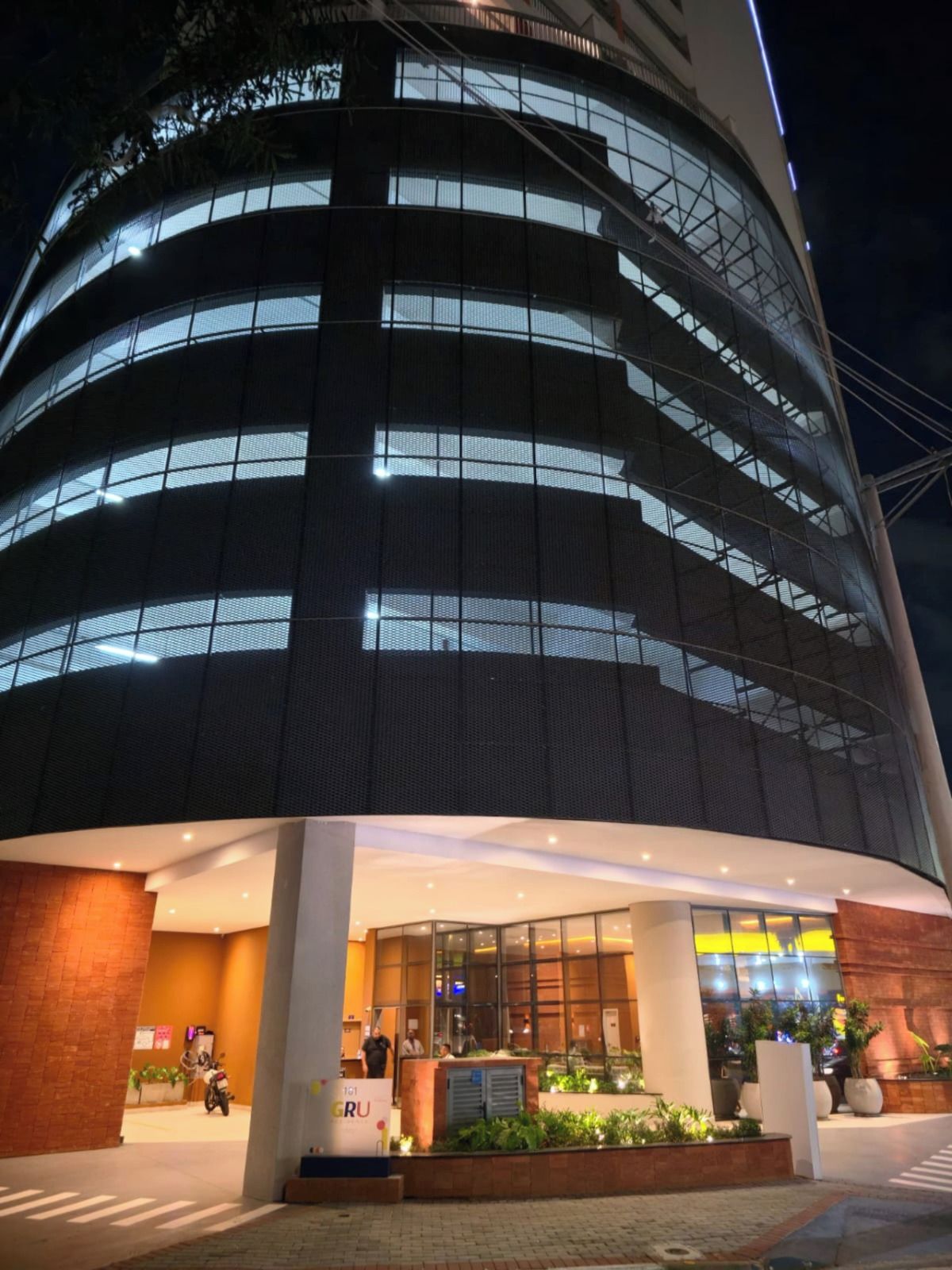 A multi-story building with a modern design, featuring a glass facade and a well-lit entrance area with a reception desk.