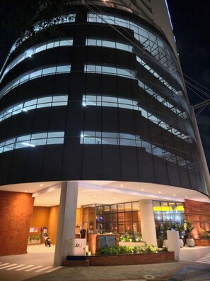 A multi-story building with a modern design, featuring a glass facade and a well-lit entrance area with a reception desk. - GRU Residence | Cozy studio on the 27th floor, close to the airport. (Guarulhos)