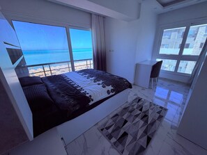 A bedroom with a large bed, a view of the sea, and a cityscape through the windows. - Fanadir Bay Luxury Sea View Apartment (Hurghada)
