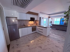 A modern kitchen with white cabinets, a stainless steel refrigerator, and a gas stove. - Fanadir Bay Luxury Sea View Apartment (Hurghada)