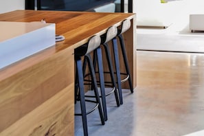 A wooden bar counter with a white sink and black barstools. - Asgard Luxury Escape (Kings Meadows)