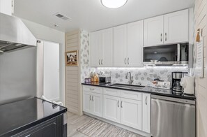 A modern kitchen with white cabinets, a stainless steel refrigerator, a microwave, and a coffee machine. - Relaxing 4-Bedroom Fort Walton Beach Retreat Stylish Baths & Family Comfort (Fort Walton Beach)
