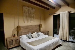 A bedroom with a bed, bedside lamps, a macrame wall hanging, and a view of the outside through a sliding door. - Cuernavaca Downtown Golf Club Boutique House with a heated pool (Cuernavaca)