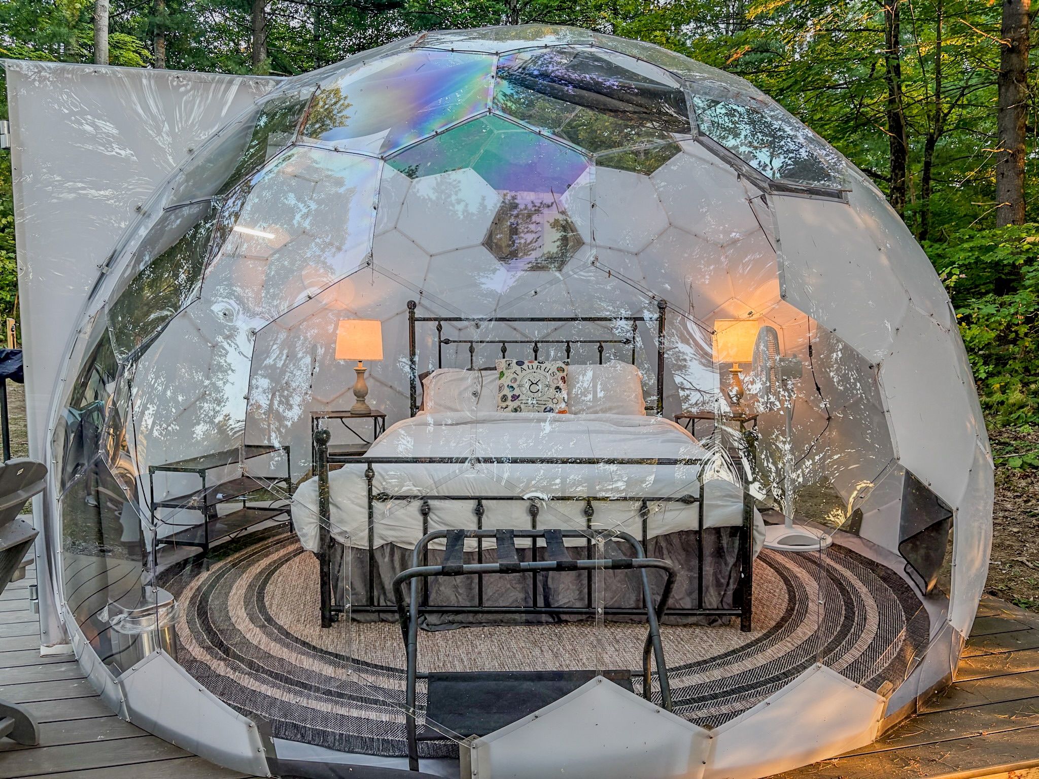A dome-shaped structure with a bed, bedside lamps, and a circular carpeted area.