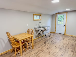 A compact kitchen with a dining area, a sink, and a window. - Taurus | Black Lake Glamping Dome (Hammond)