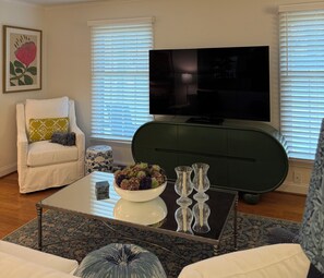 Ein Wohnzimmer mit einer Couch, einem Couchtisch mit Dekoration, einem Fernseher und einem grünen Akzentstuhl.