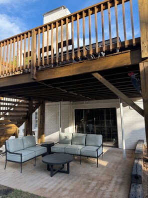 Ein überdachter Außenbereich mit einer Holz-Pergola, einer Couch und einem runden Tisch.
