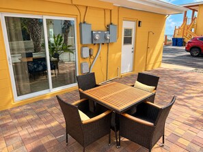Eine Terrasse mit Tisch und Stühlen, eine Glasschiebetür und Außenstromkästen.