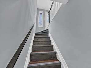 A staircase with a handrail, leading to a door with a window. - 4BR Home | Fenced Yard & 2-Car Parking (Windsor)