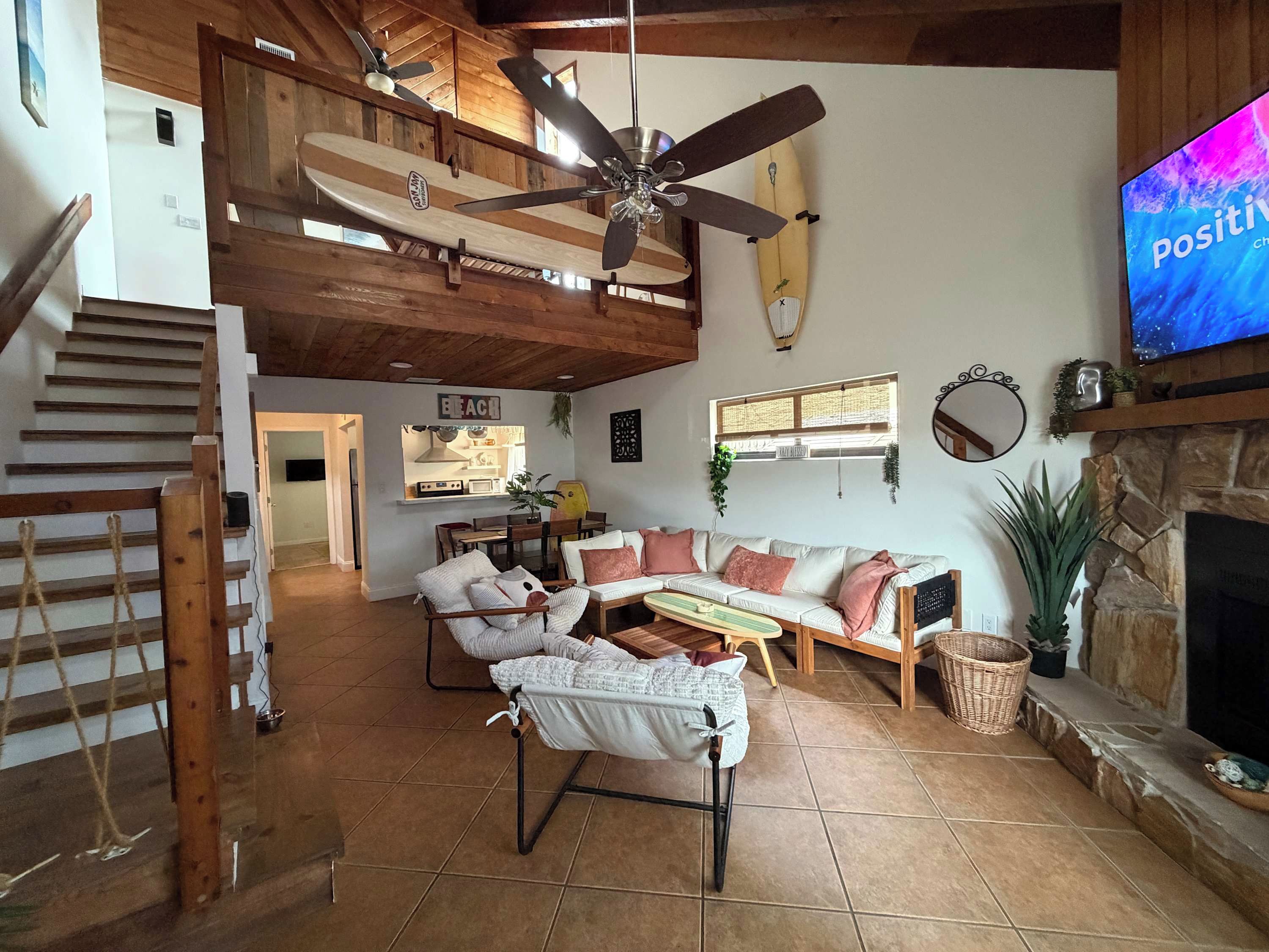 A spacious living room with a high ceiling, a fireplace, a television, and a dining area.