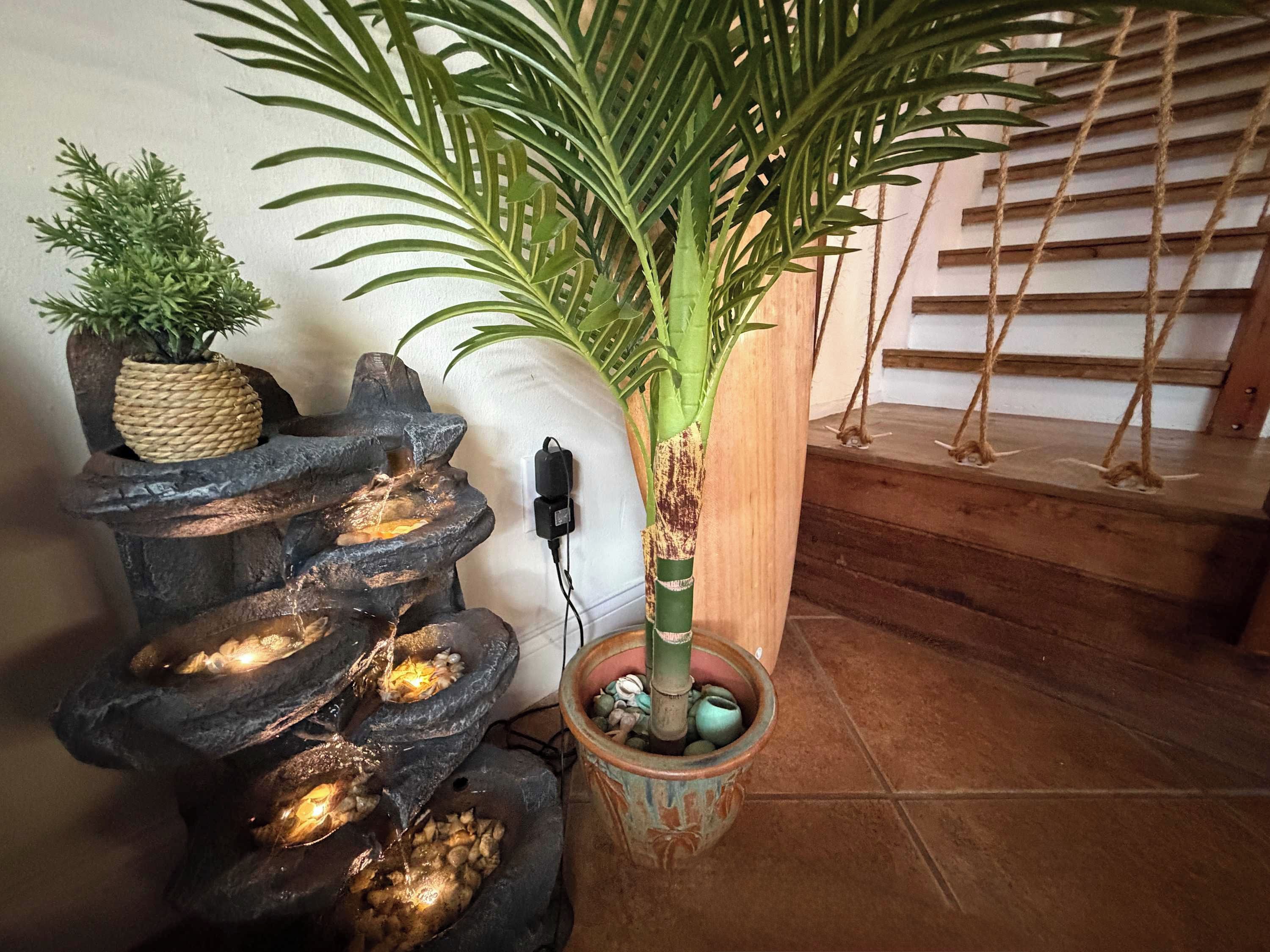 A water feature with cascading streams, a potted plant, and a staircase with wooden railings.