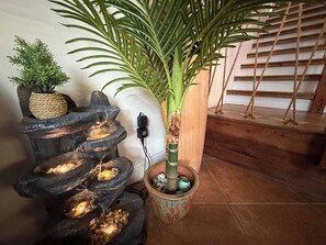 A water feature with cascading streams, a potted plant, and a staircase with wooden railings.