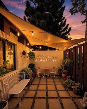 An outdoor seating area with a table and chairs, a bench, and potted plants.