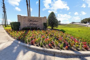 A sign for Windsor Palms, a gated resort community, with a landscaped flower bed in front. - Condo 2BR en Windsor Palms cerca de Disney (Kissimmee)