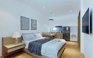 Un dormitorio moderno con cama, mesita de noche y un pequeño escritorio. Cuenta con una zona de cocina con refrigerador, lavadora y mesa de comedor con sillas.
