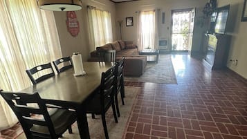 A spacious living area with a dining table, chairs, a sofa, and a television.