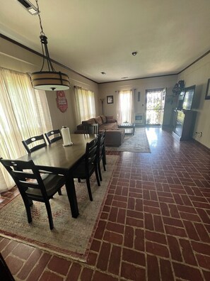 Amplia sala de estar con mesa de comedor, sillas, sofá y televisor.