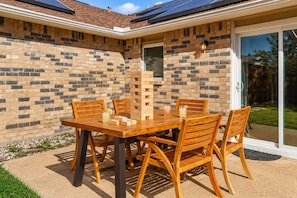 A patio with a brick wall, a wooden table, and chairs. - Family Friendly, Near The Lake, Games, BBQ, More (The Colony)