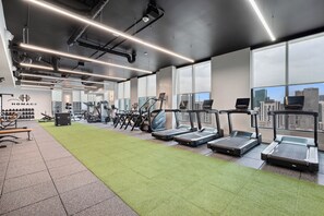 A gym with treadmills, weight machines, and a green turf area. - 501 First Loft Balcony by Palermo Home (Miami)