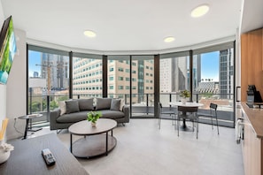 A modern living room with a sofa, a coffee table, and a dining area with chairs. - 501 First Loft Balcony by Palermo Home (Miami)