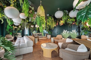 A modern lounge area with a sofa, chairs, a round wooden table, and hanging plants. - 501 First Loft Balcony by Palermo Home (Miami)