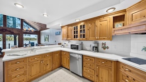 A modern kitchen with wooden cabinets, a dishwasher, and a view of a lake.